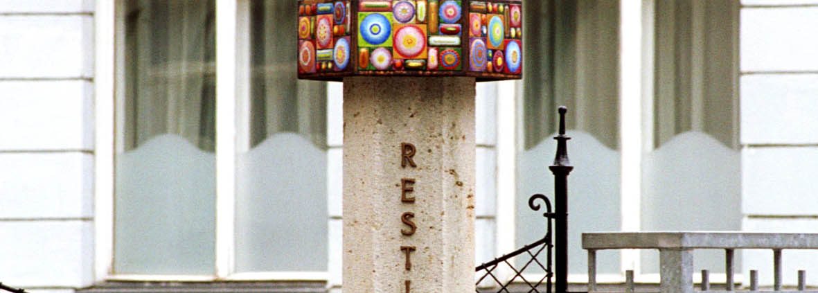 Foto: Säule mit Aufschrift "Restituta" und einem Kreuz, umgeben von einem bunten Ring