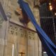 Foto: die Restituta-Büste von Hrdlicka wird enthüllt. Sie hängt an der Wand in der Kapelle, ein dunkelblaues Tuch, das sie verdeckt, hebt sich